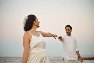 A man and woman standing on a beach next to the ocean