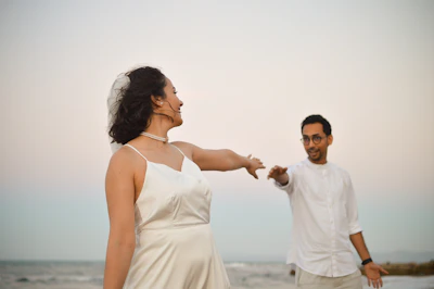 A man and woman standing on a beach next to the ocean