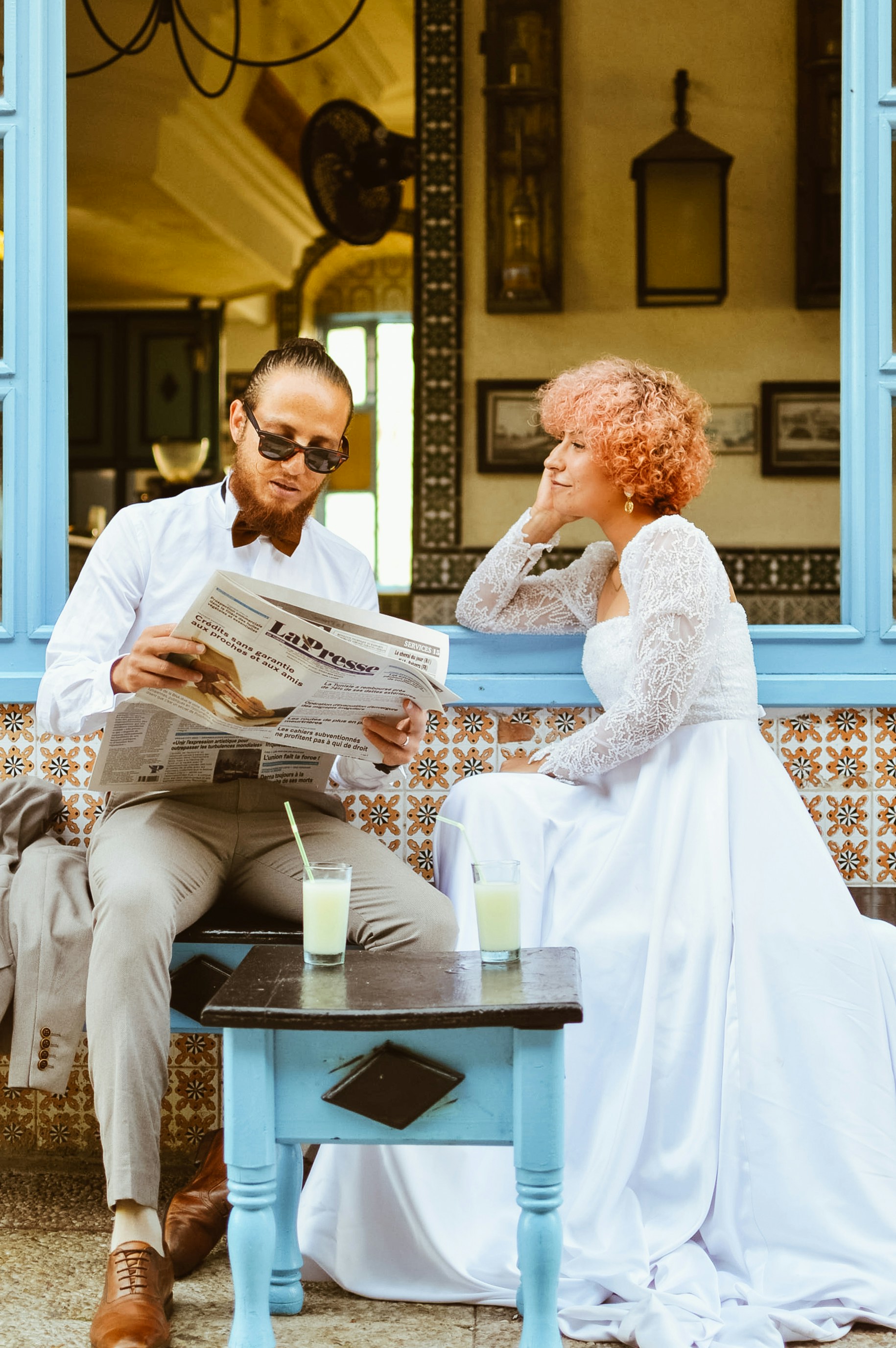 Um homem e uma mulher sentados em um banco lendo um jornal