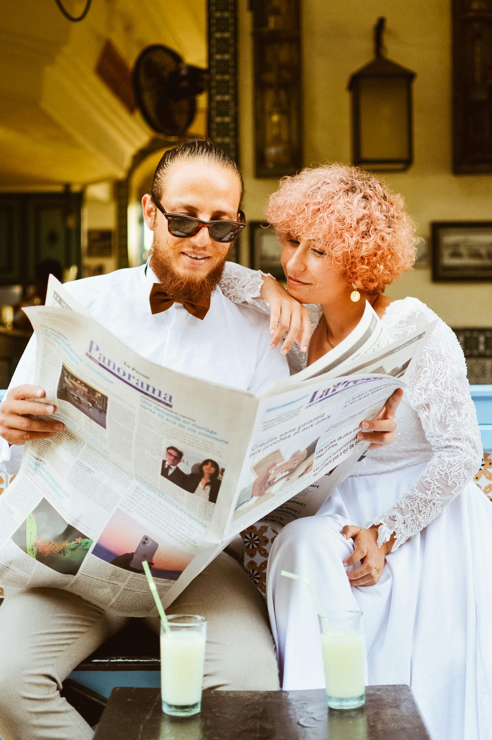 A man and woman sitting on a bench reading a newspaper
