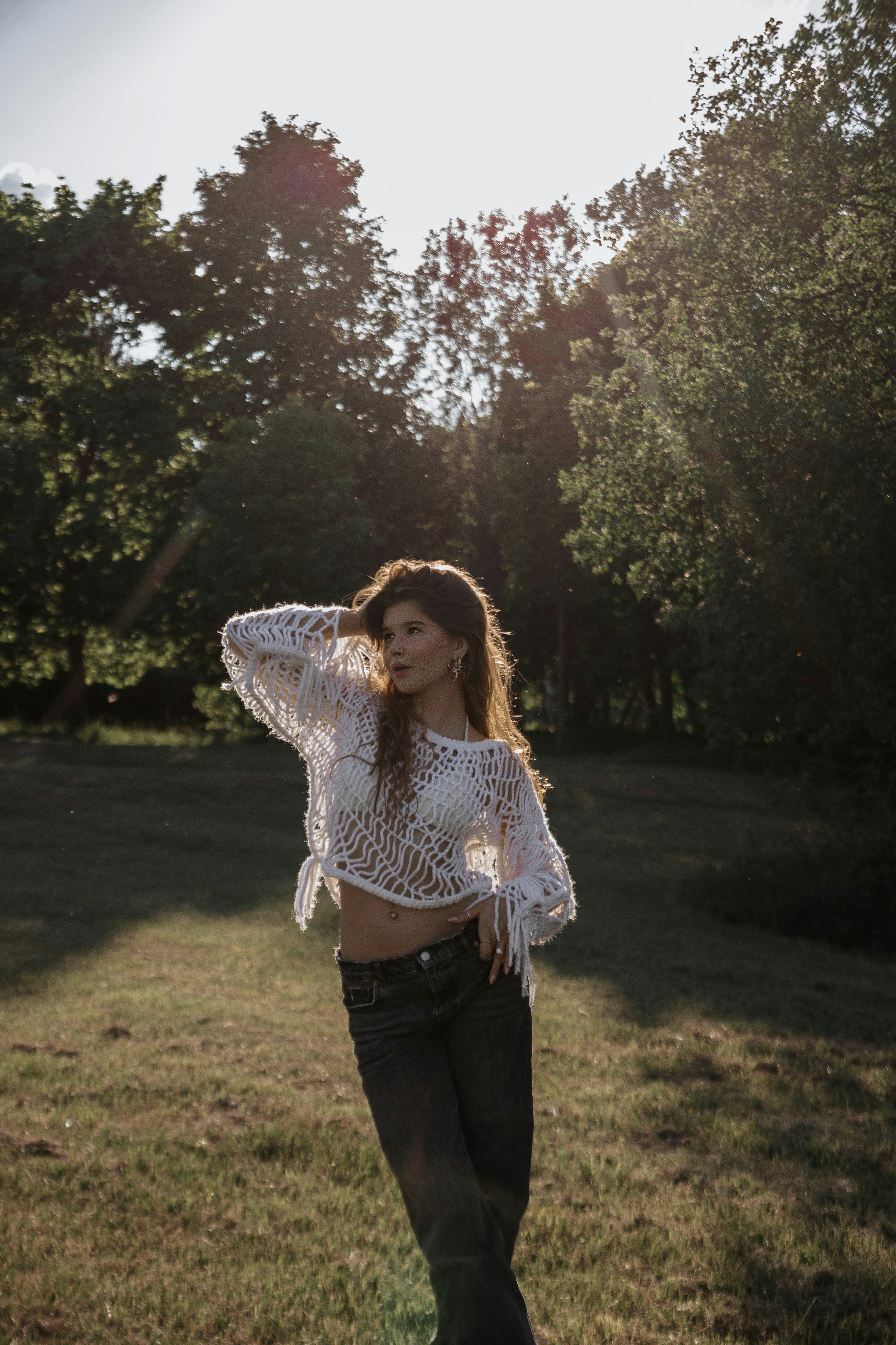 A woman standing in a field with trees in the background