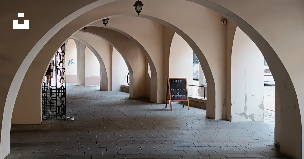 A long hallway with arches and a clock on the wall photo – Free ...