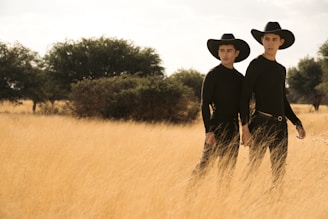 Two people in black outfits standing in a field