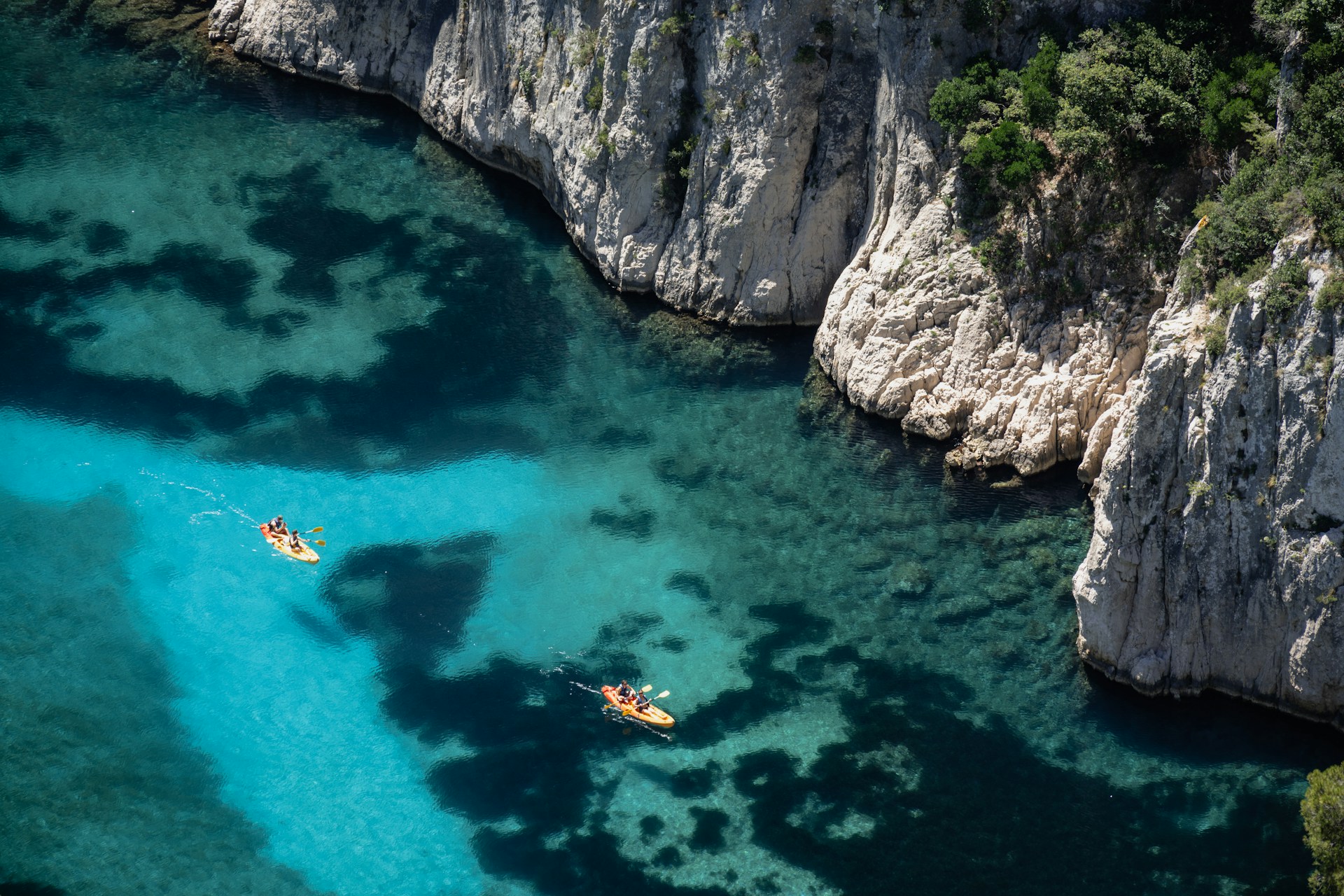 Two people are kayaking in the clear blue water