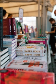 A number of books on a table with people in the background