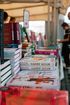 A number of books on a table with people in the background