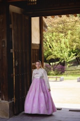 A woman in a pink and white dress standing in a doorway