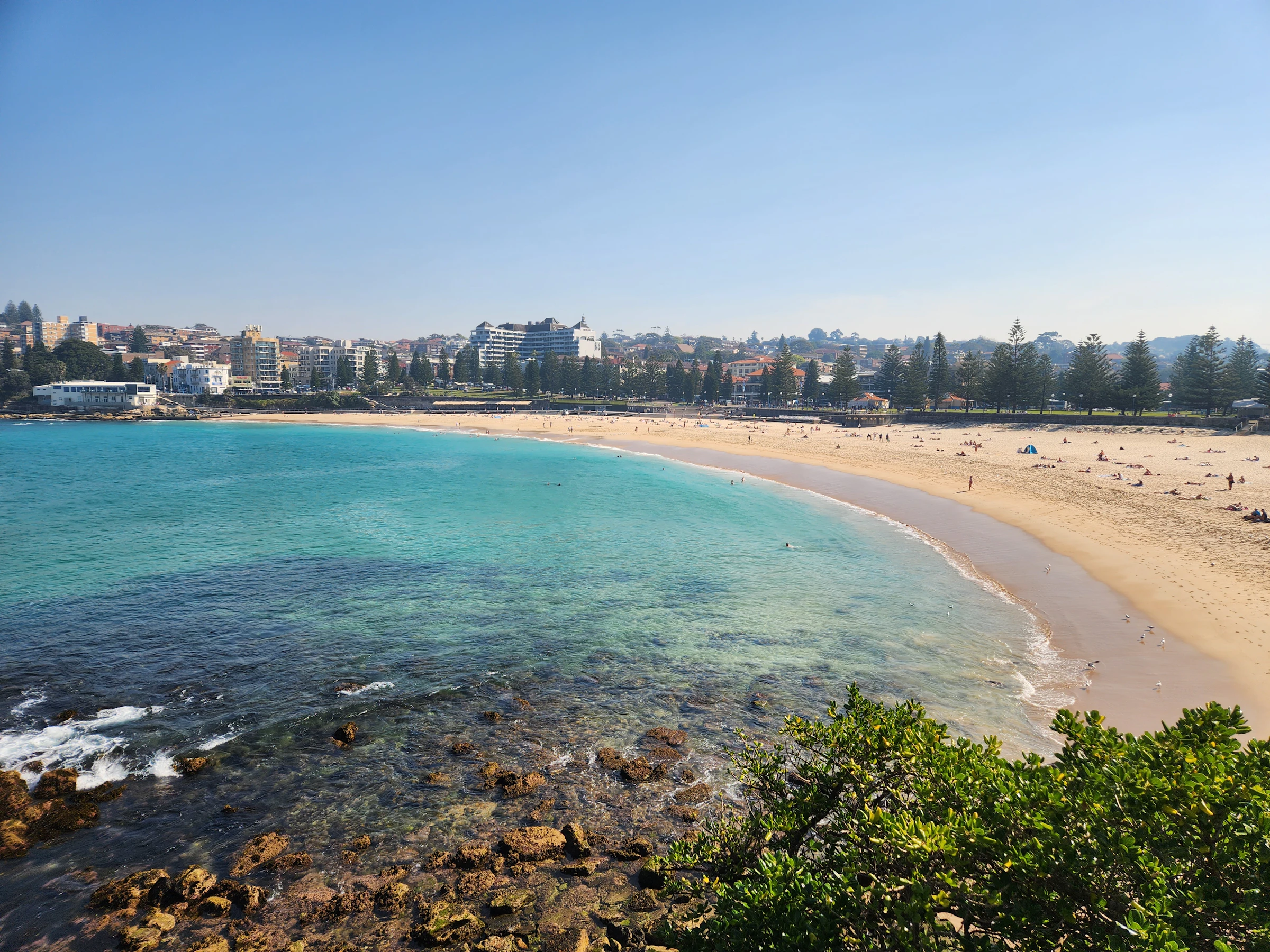 A wide sunny Australian coastline with a city in the distance