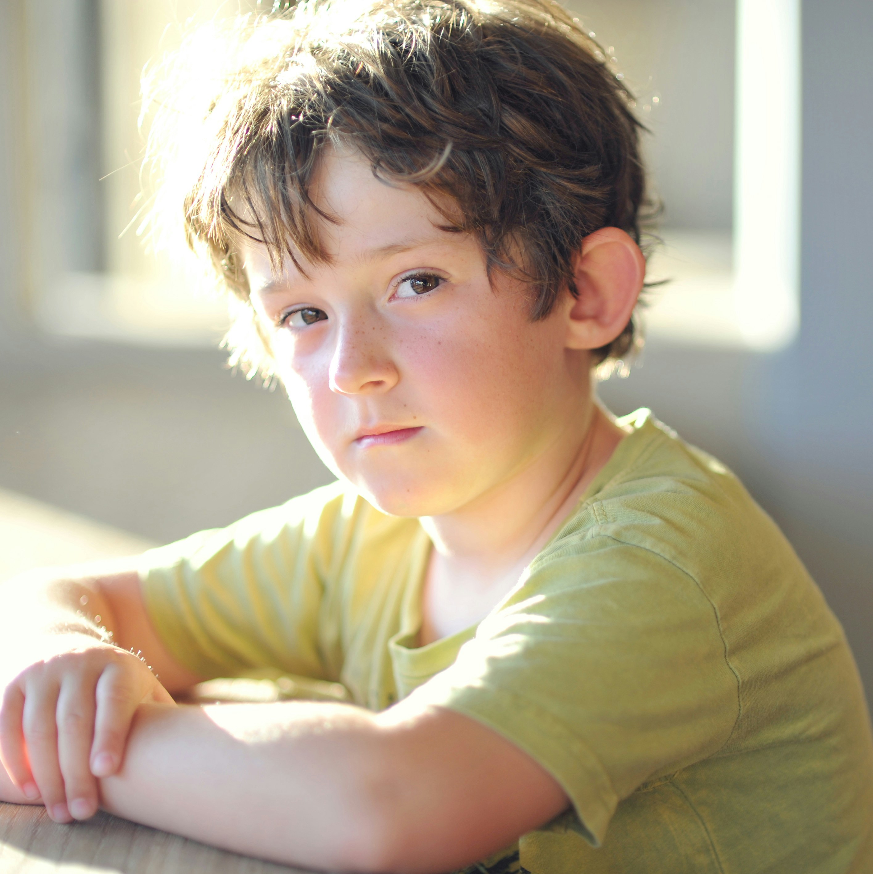 A young boy sitting at a table with his arms crossed