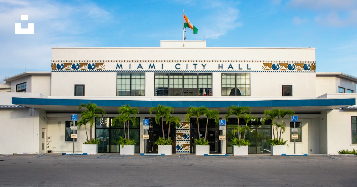 A Large White Building With A Flag On Top Of It Photo Free Miami City a-large-white-building-with-a-flag-on-top-of-it-photo-free-miami-city