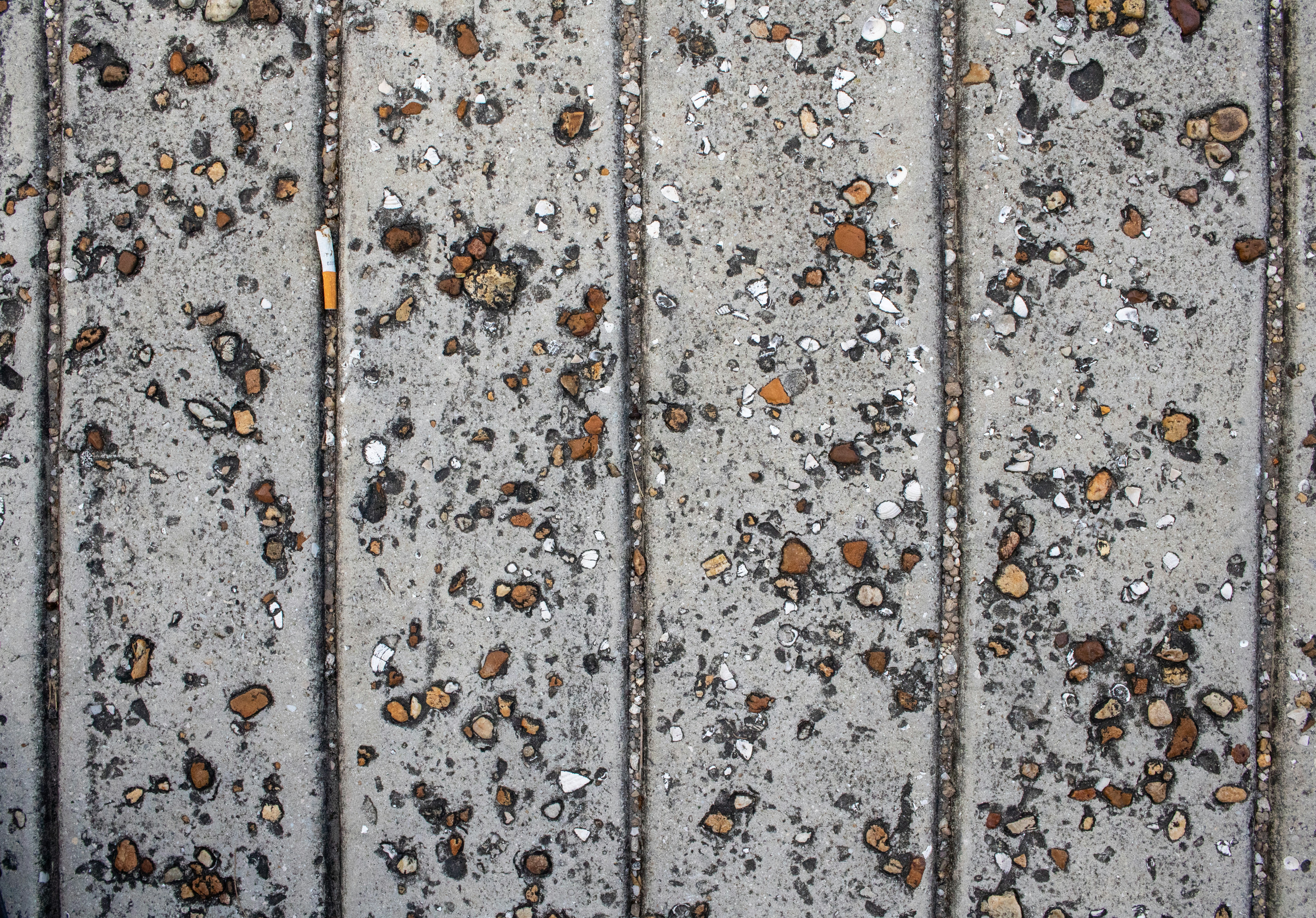 Textured concrete surface with embedded stones, illustrating hardscape elements for outdoor design.