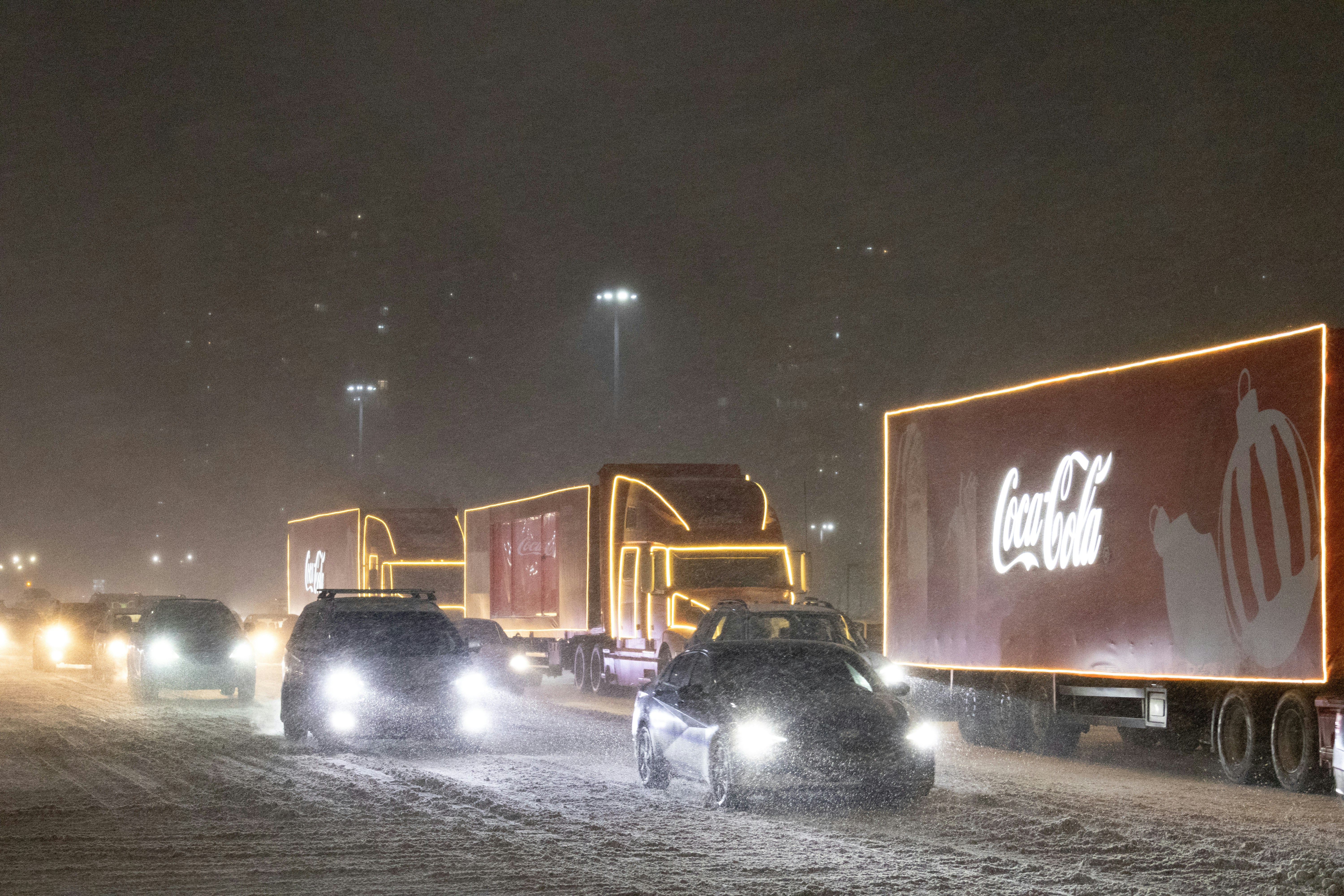 A group of cars driving down a snow covered road