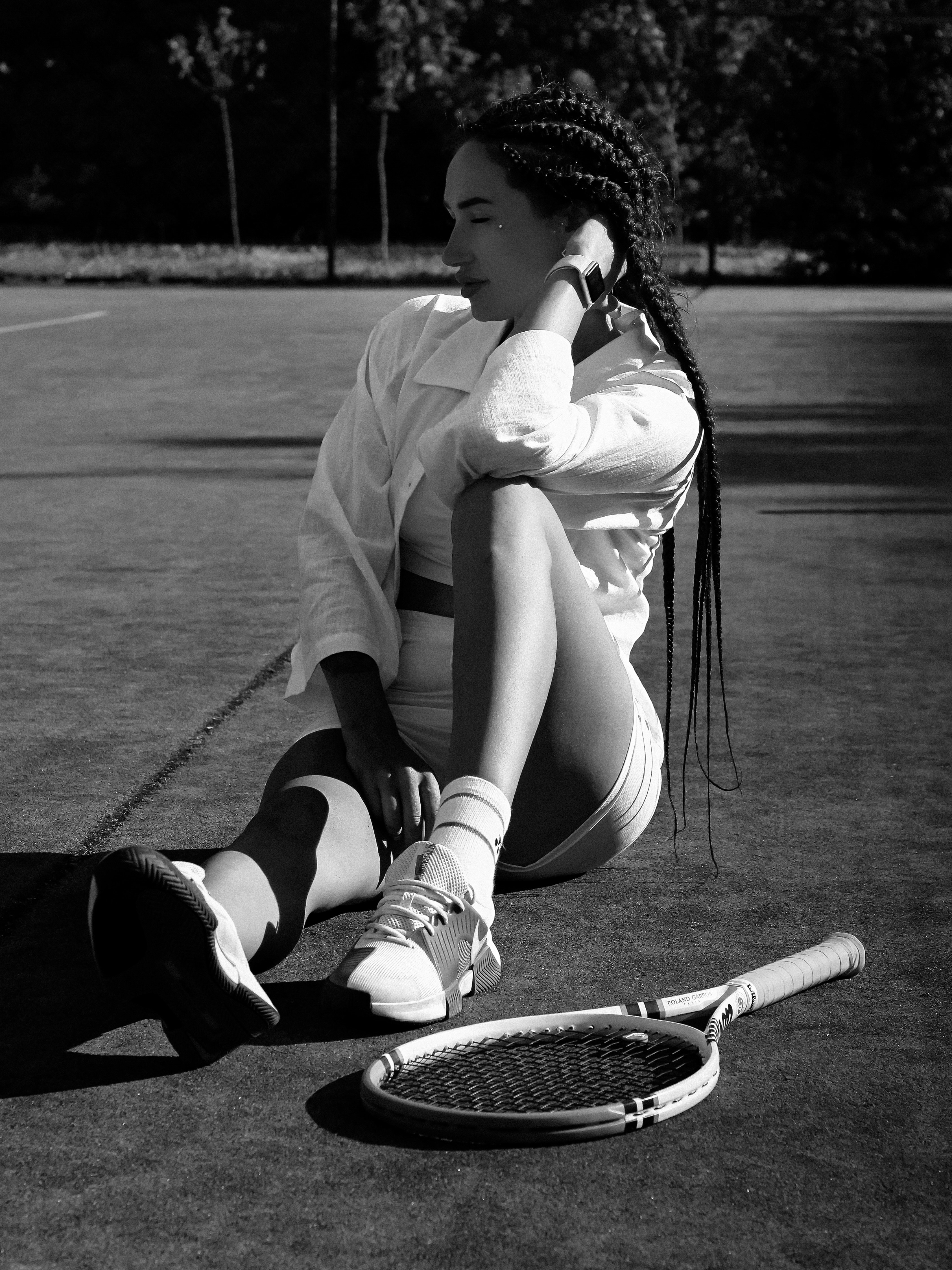 A woman sitting on the ground with a tennis racket