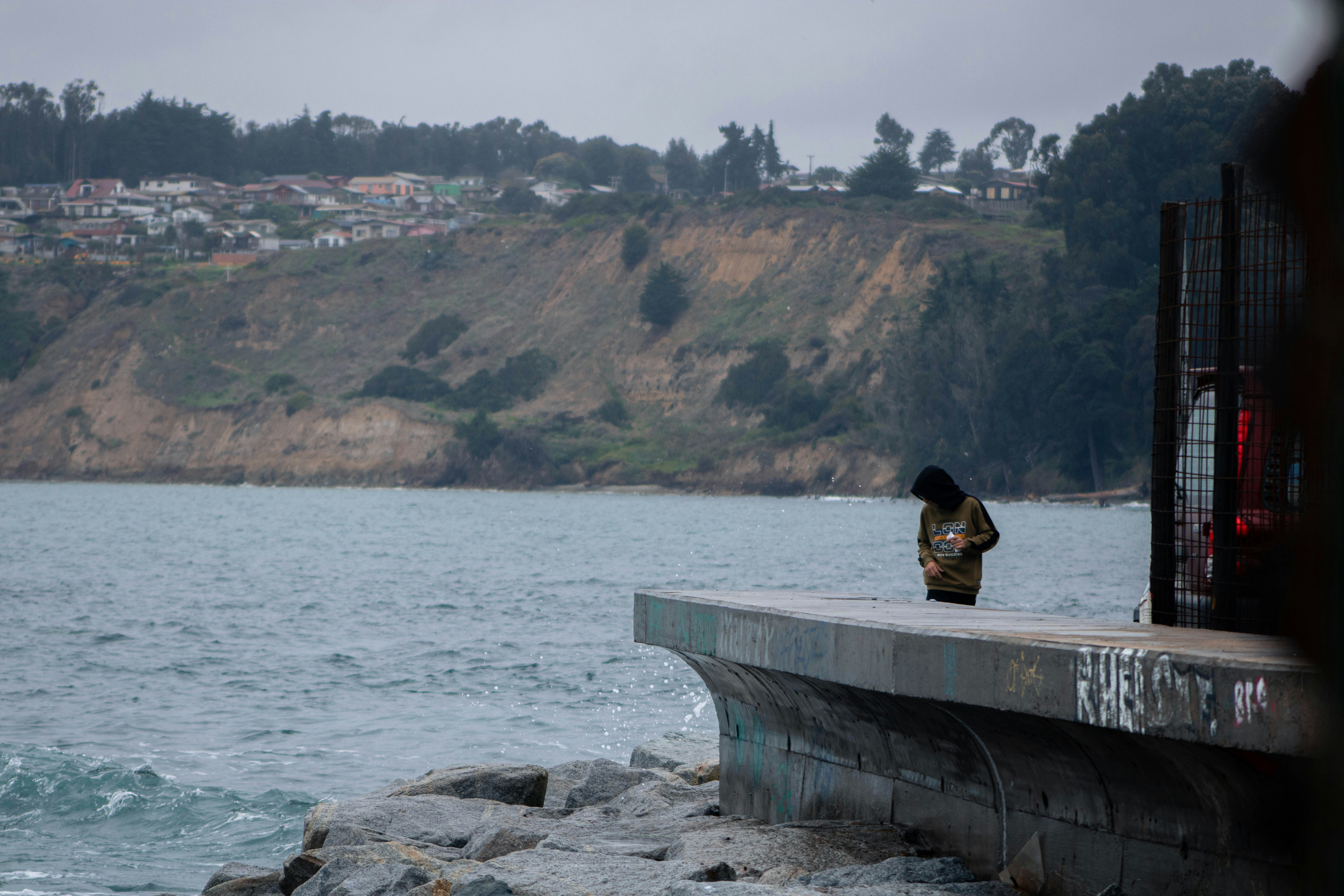A person sitting on a ledge overlooking a body of water