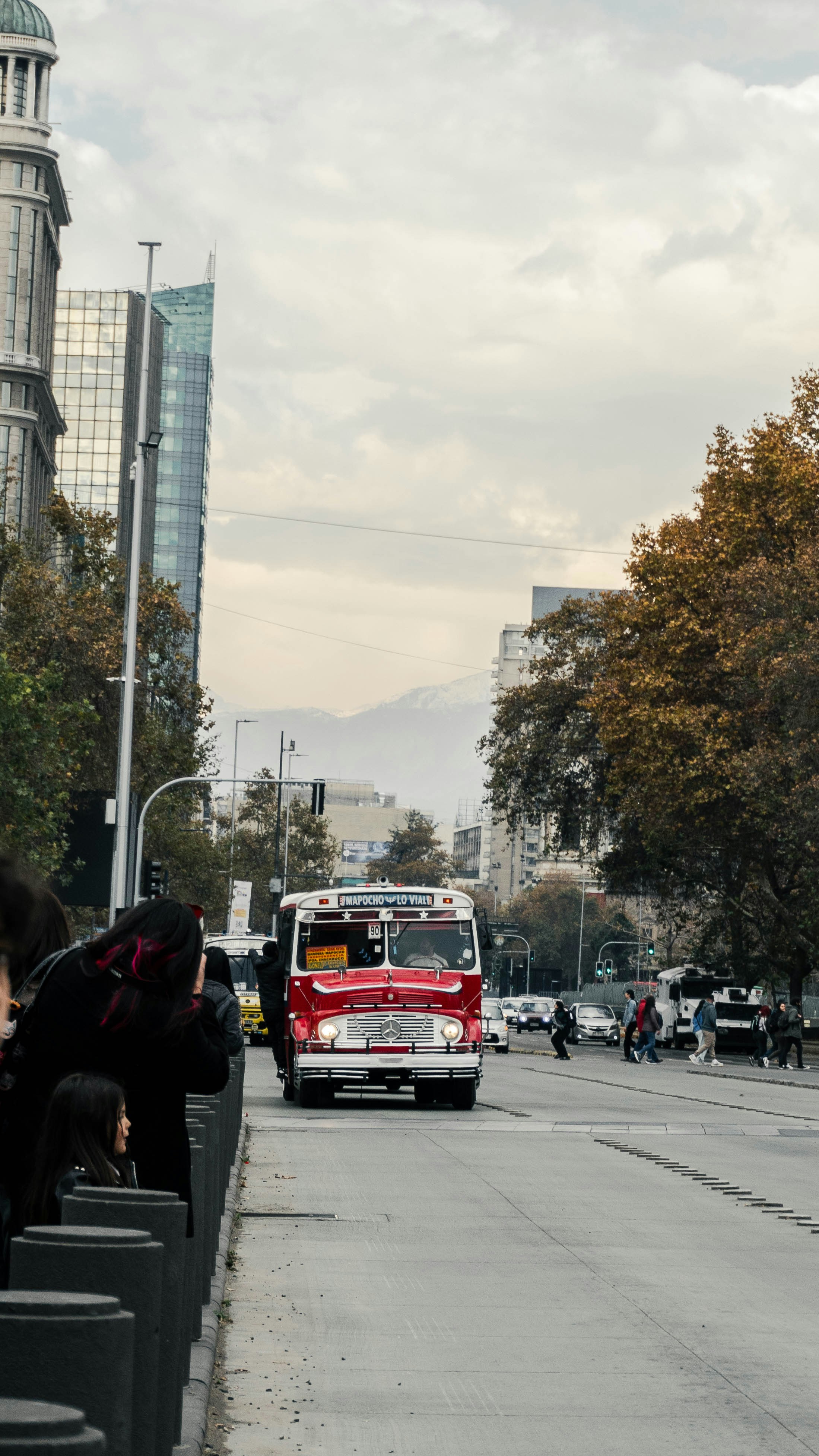 A red bus driving down a street next to tall buildings