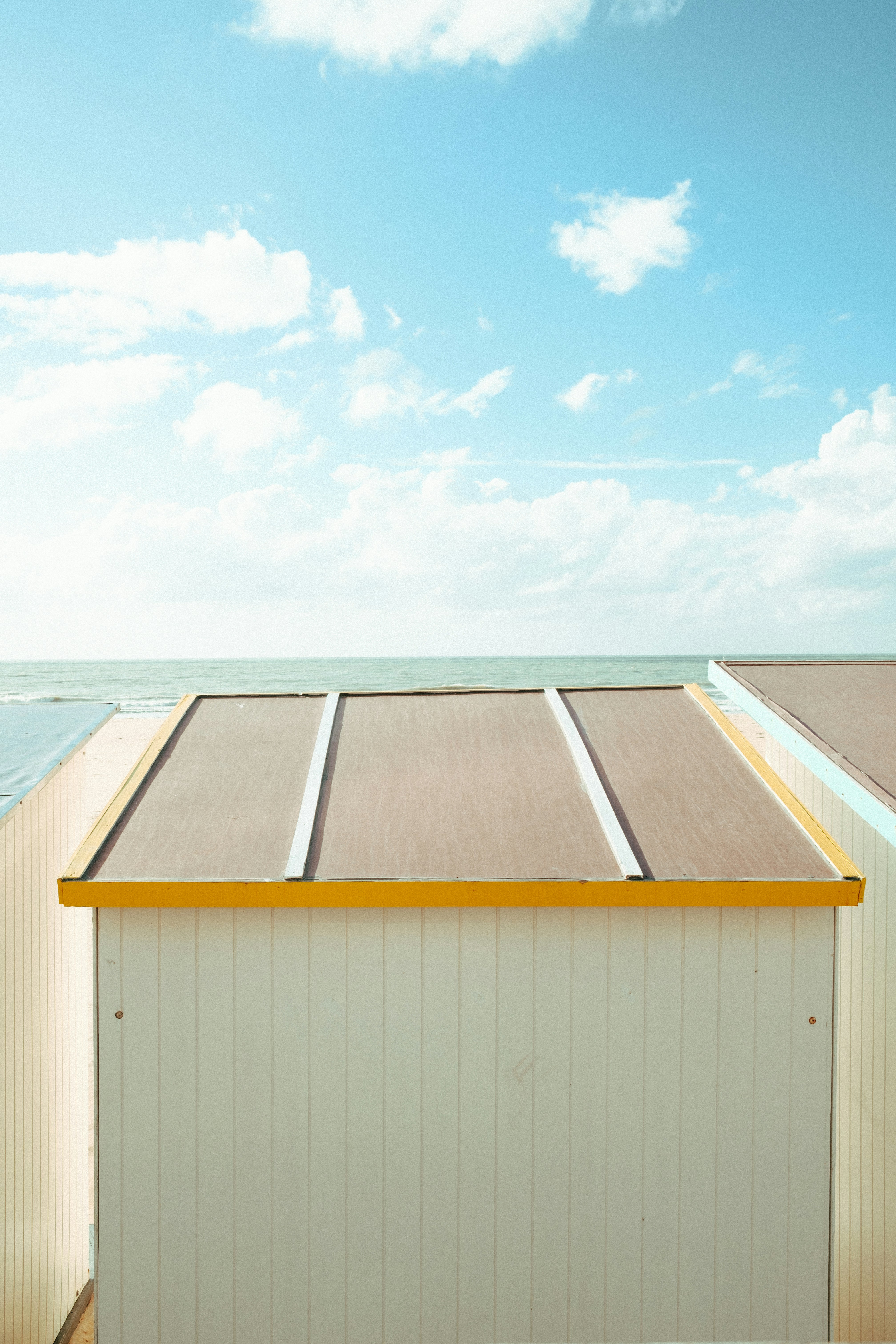 Un bâtiment blanc et jaune assis au sommet d’une plage