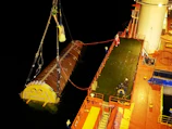 A large boat with a giant yellow object on it's side