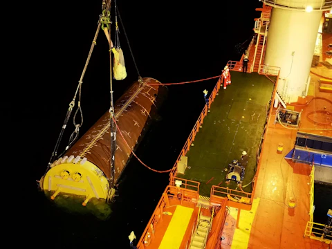 A large boat with a giant yellow object on it's side