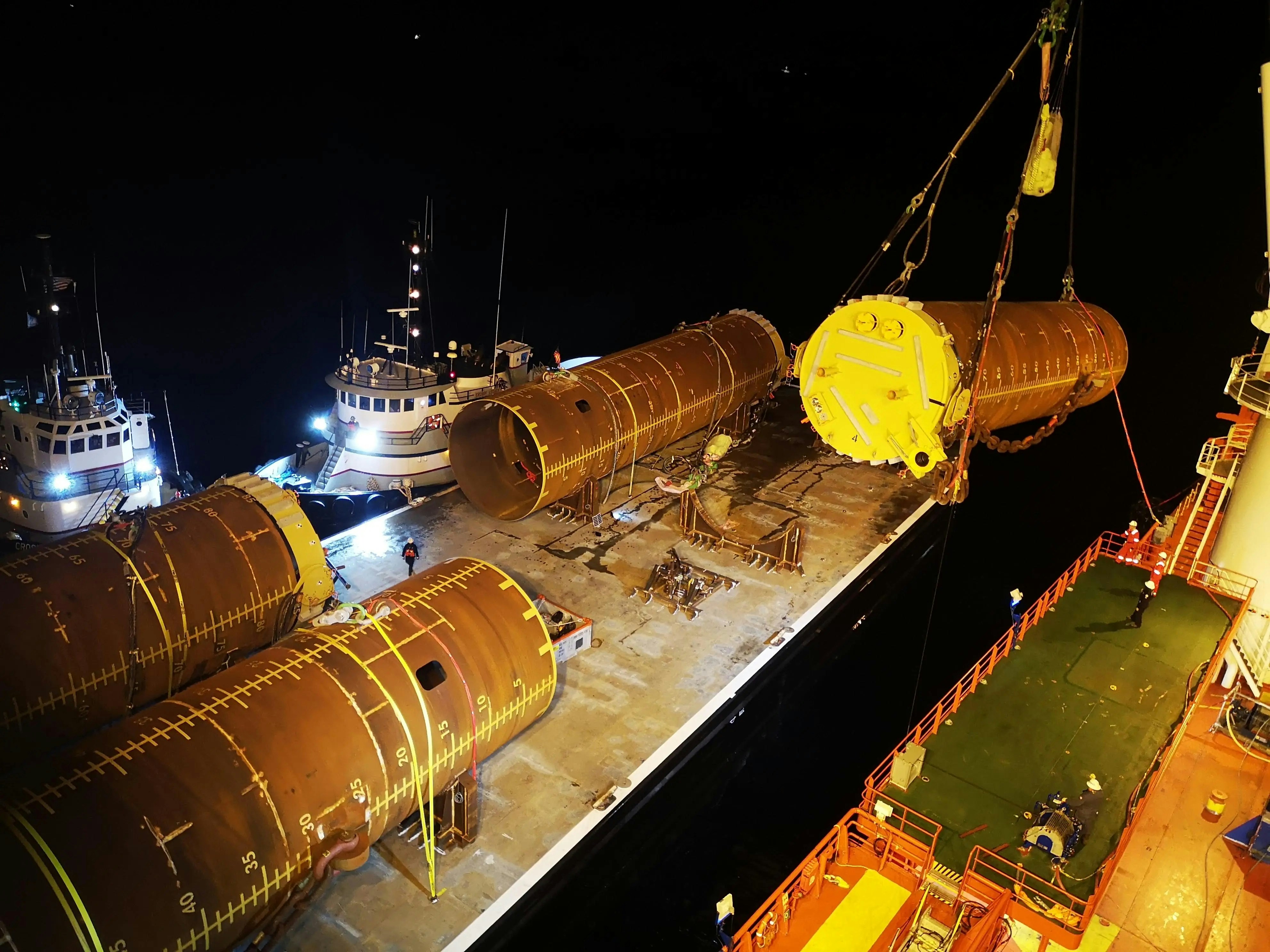 A large ship is docked at night with other boats