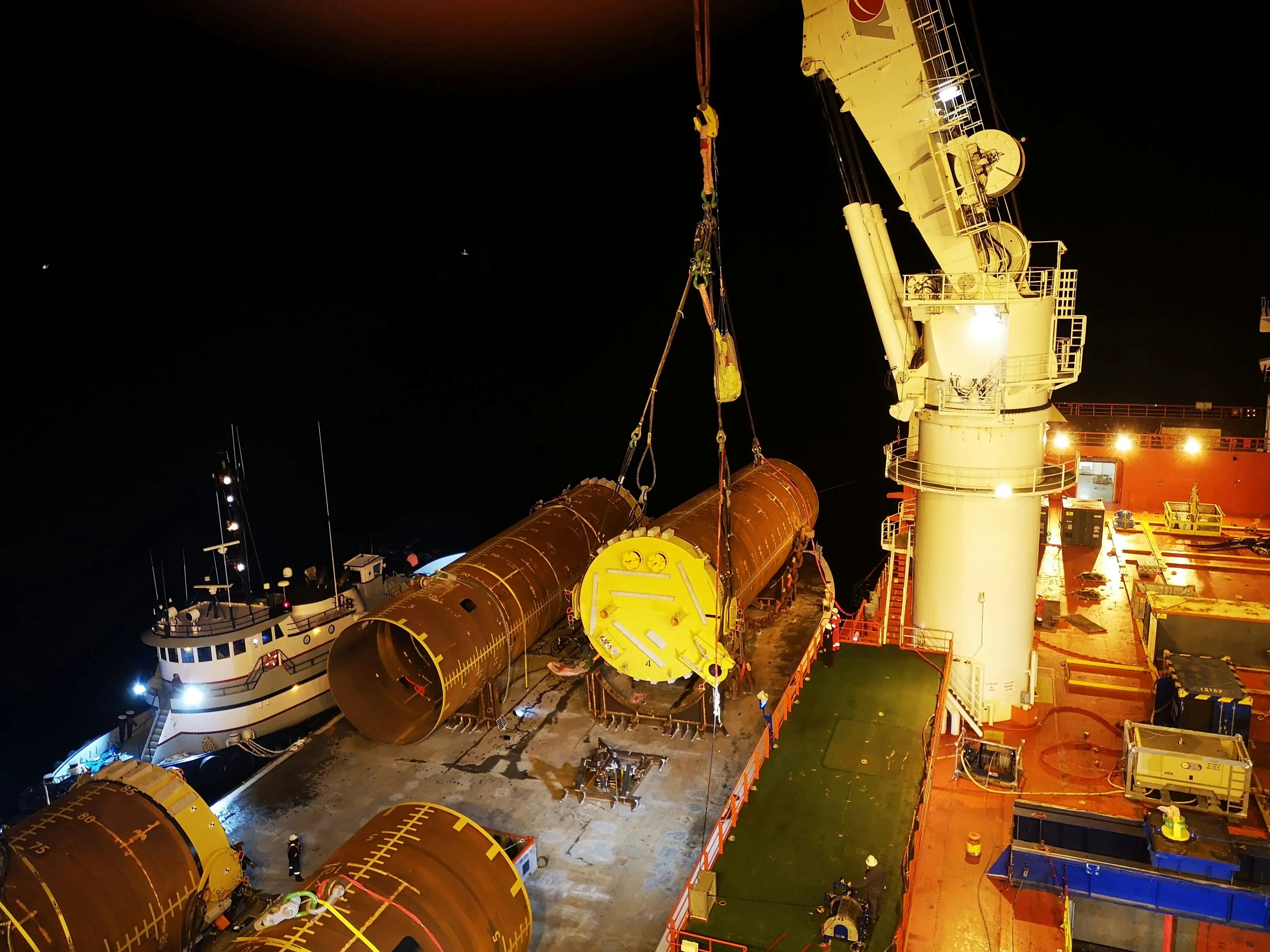 A crane is lifting logs onto a ship