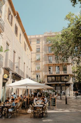 A group of people sitting at tables under umbrellas