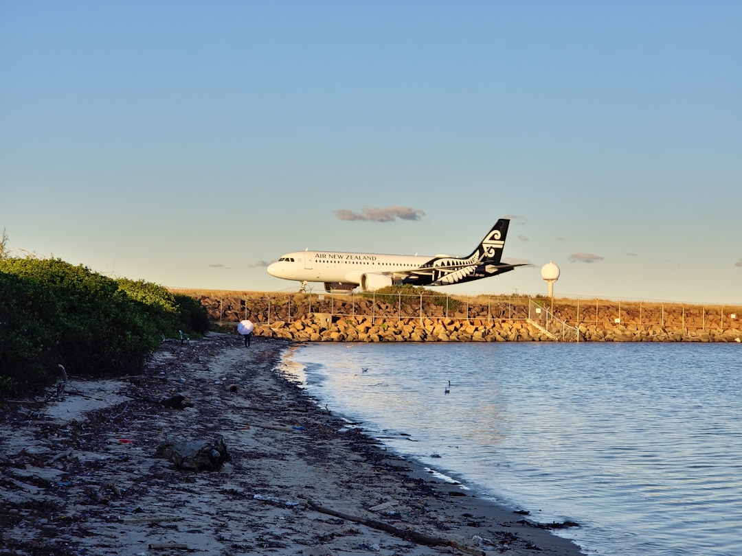 A plane flying low over a body of water, Air New Zealand airplane over beach