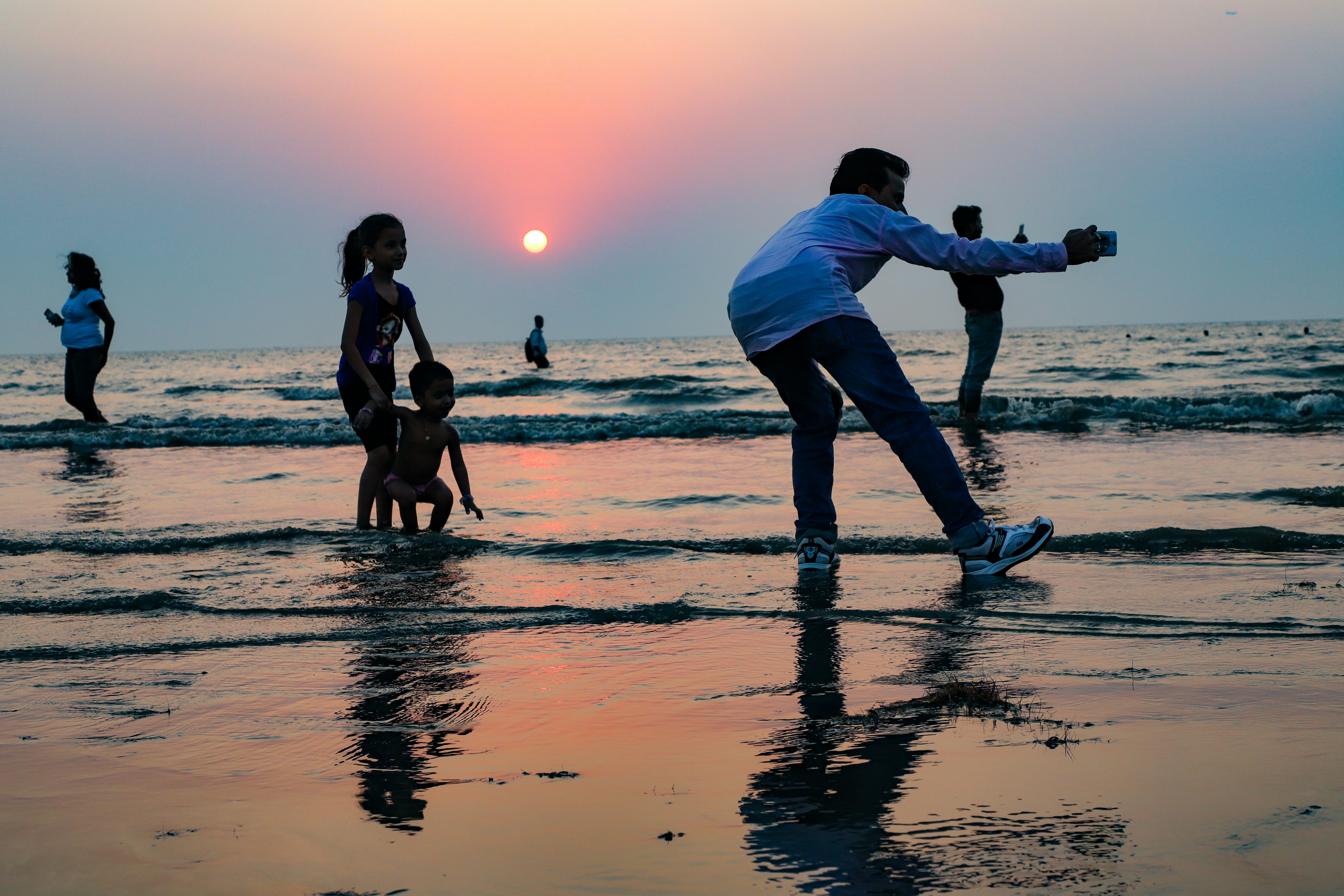 A group of people standing on top of a beach next to the ocean