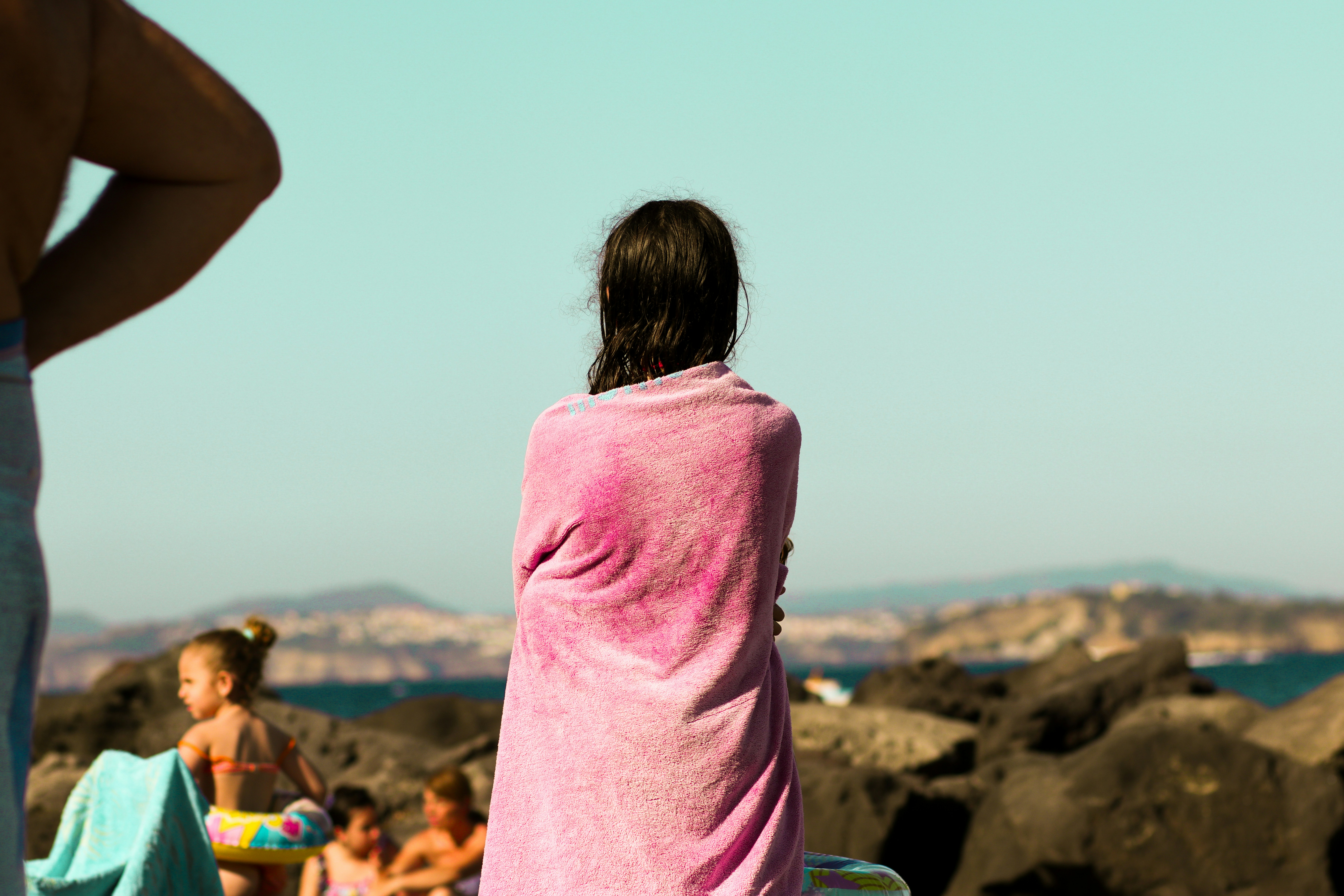 Eine Frau in einem rosa Handtuch steht an einem Strand
