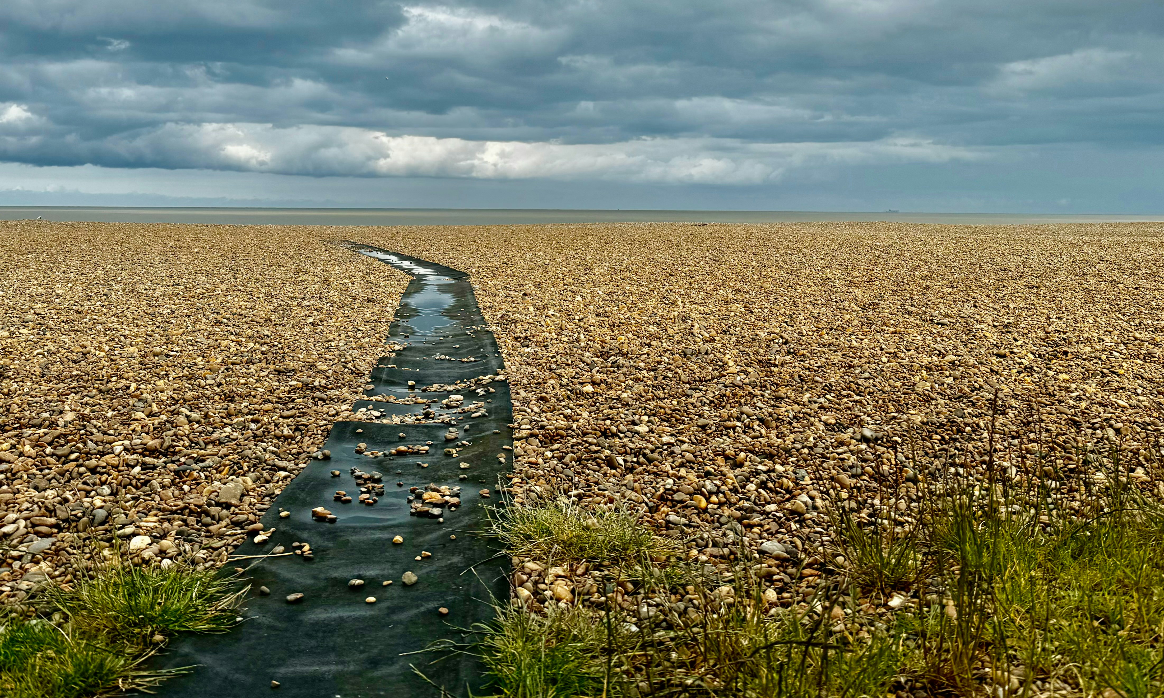 A long stream running through a dry grass field