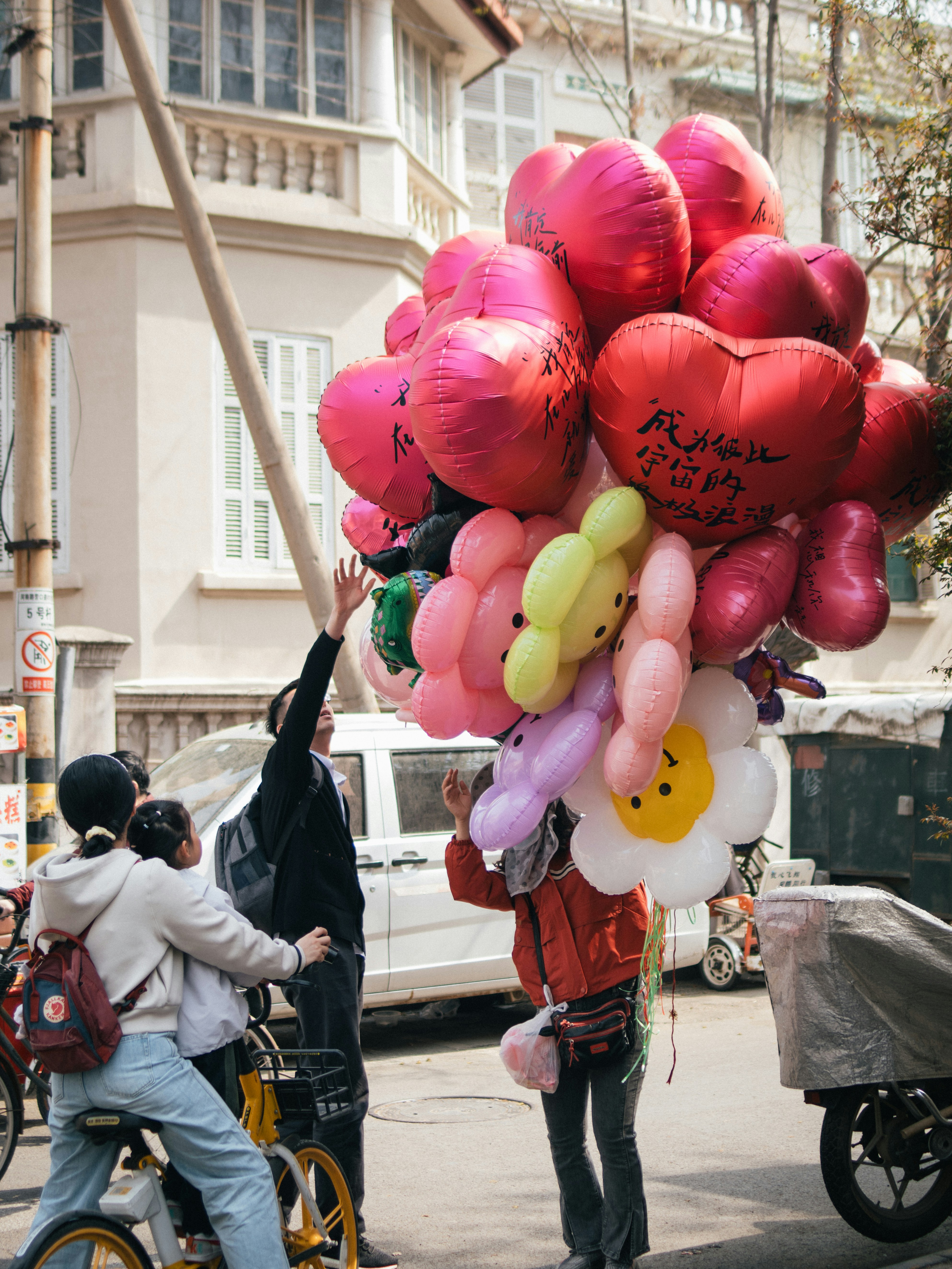 A person on a bike holding a bunch of balloons