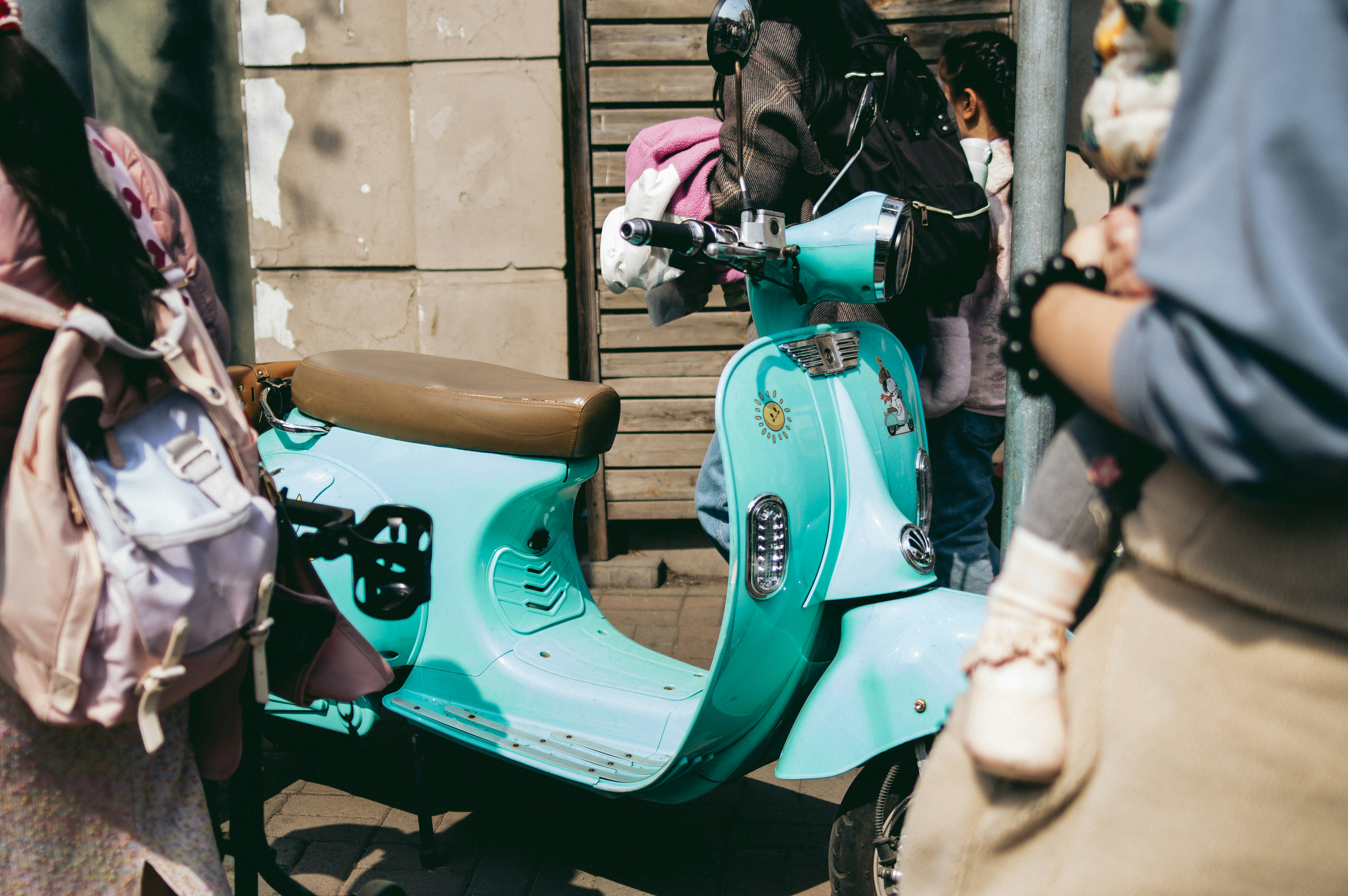 A woman standing next to a blue scooter