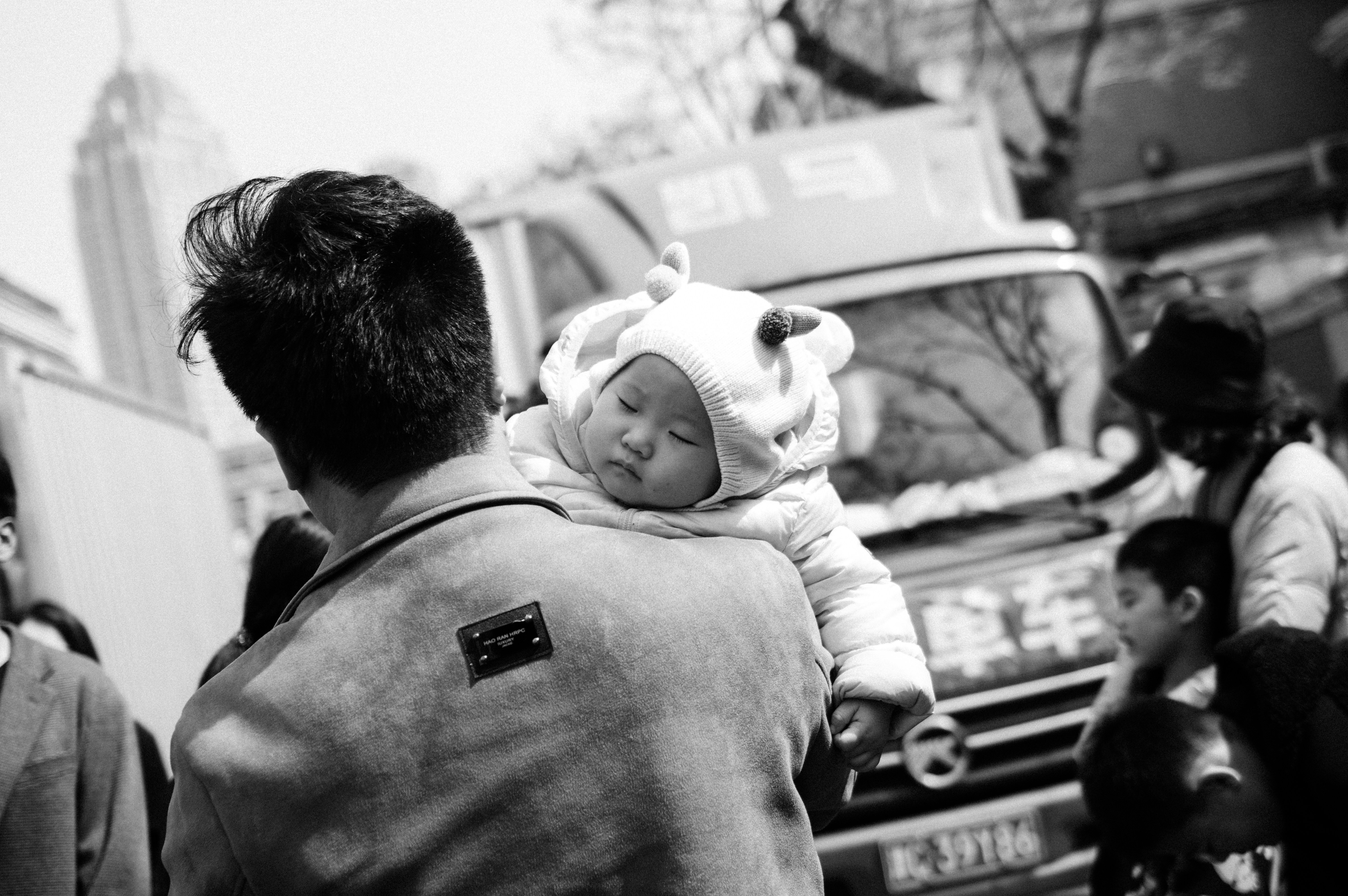 A black and white photo of a man carrying a baby