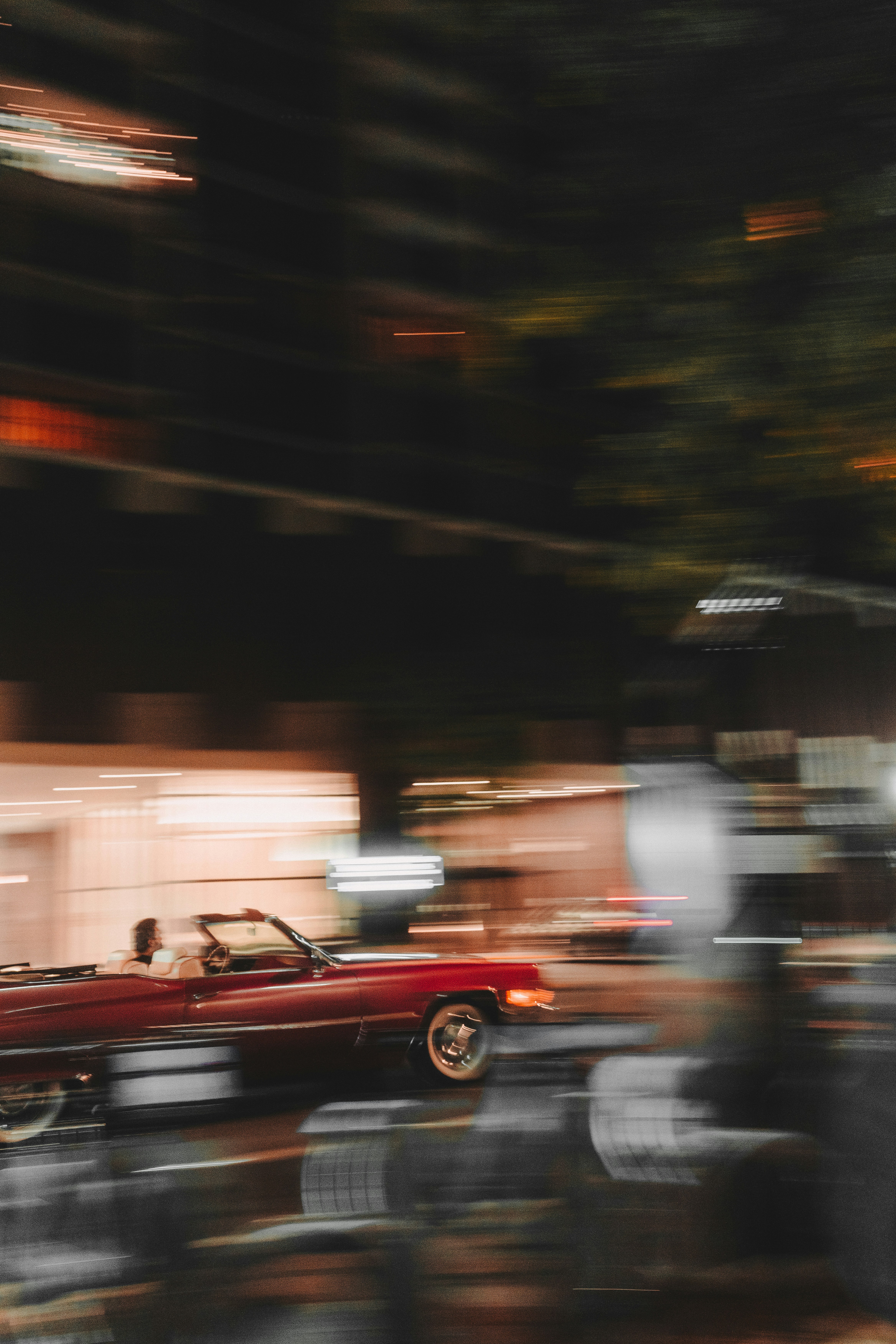 Ein rotes Auto fährt eine Straße neben einem hohen Gebäude hinunter