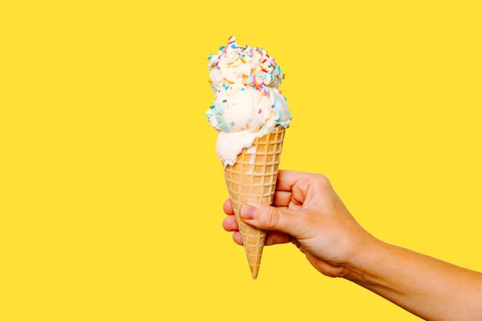 Hand holding a scoop of ice cream in a cone