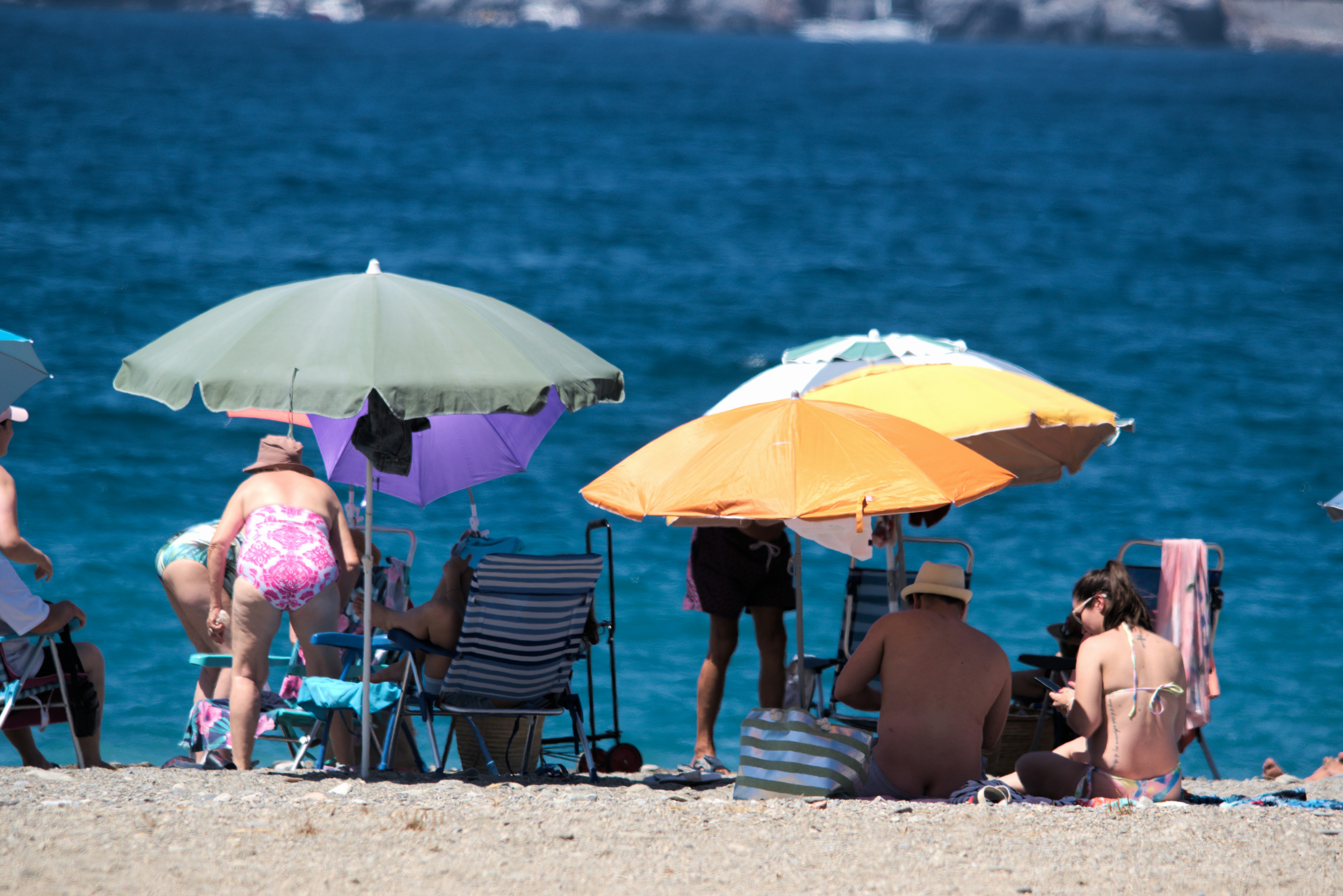 A group of people sitting under umbrellas on a beach