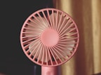 A pink fan sitting on top of a table