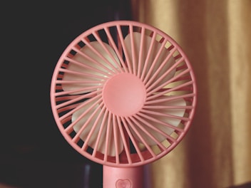 A pink fan sitting on top of a table