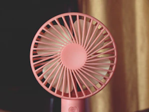 A pink fan sitting on top of a table