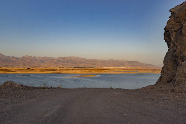 A dirt road next to a body of water