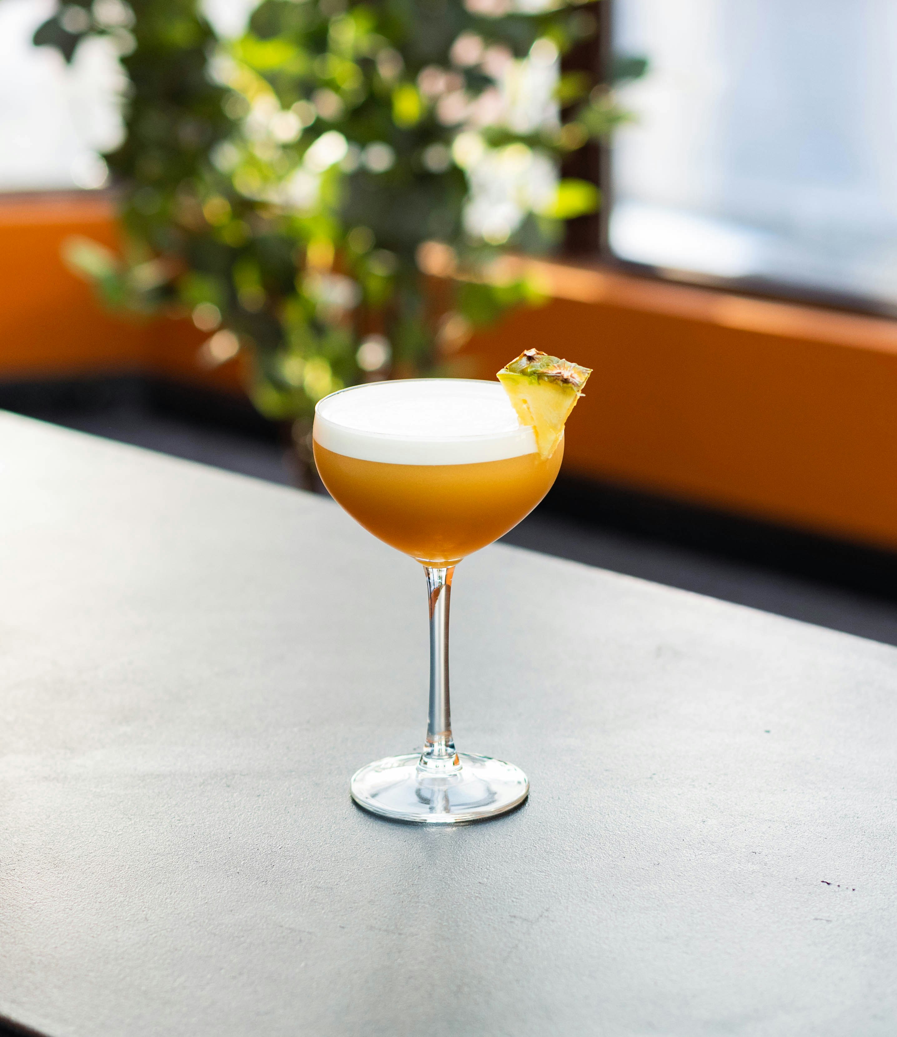 A drink sitting on top of a table next to a potted plant
