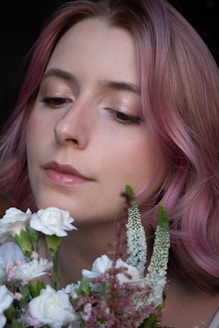 A woman with pink hair holding a bouquet of flowers