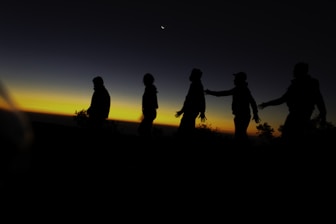A group of people walking across a field at sunset