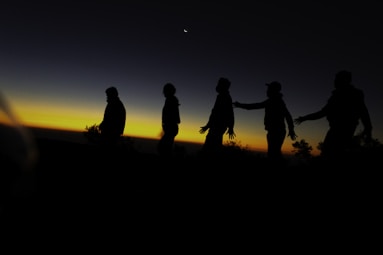 A group of people walking across a field at sunset