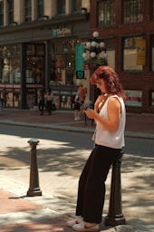 A woman standing on the side of a street using a cell phone