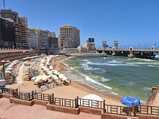 A sandy beach with umbrellas and buildings in the background