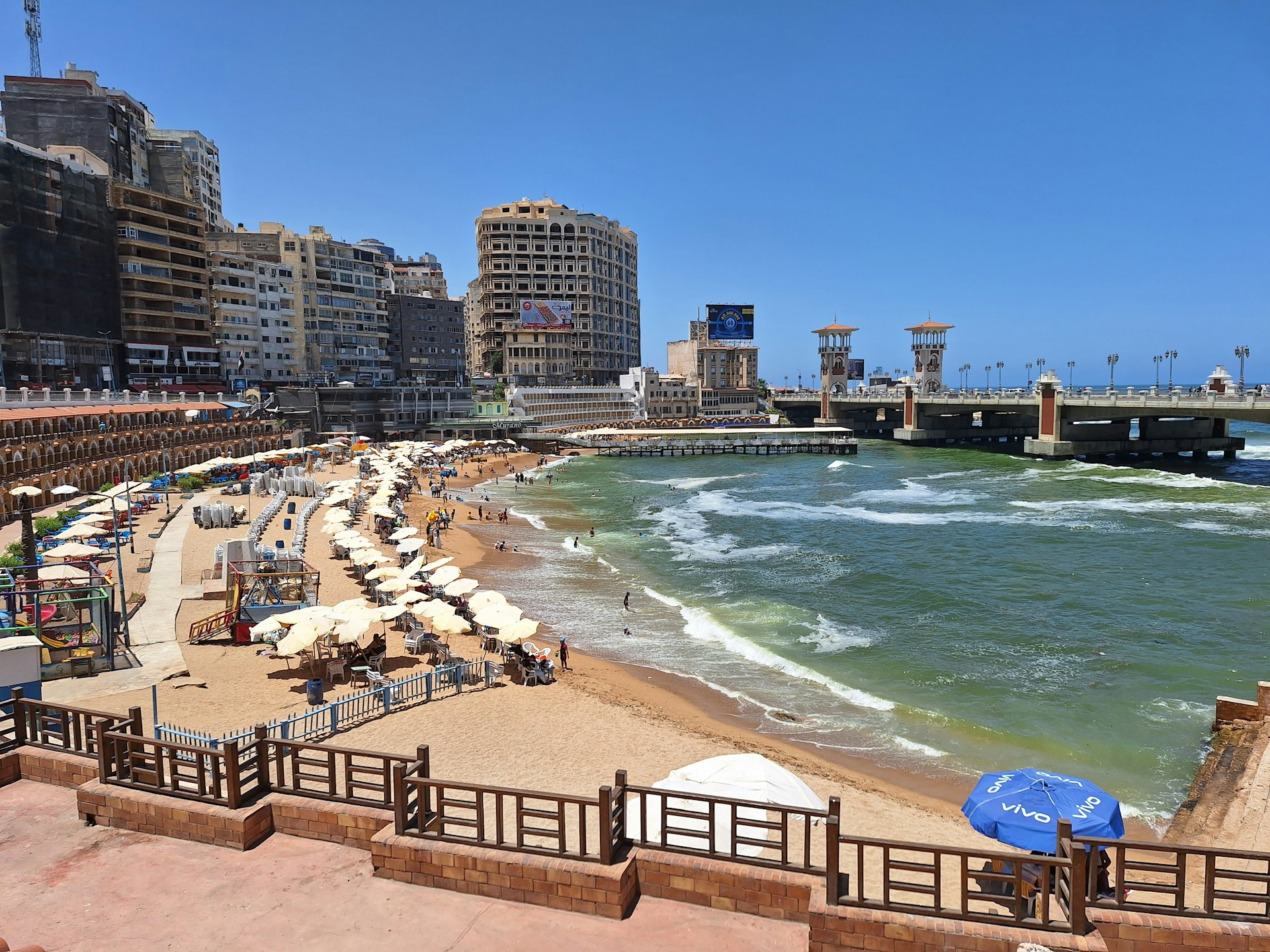 A sandy beach with umbrellas and buildings in the background