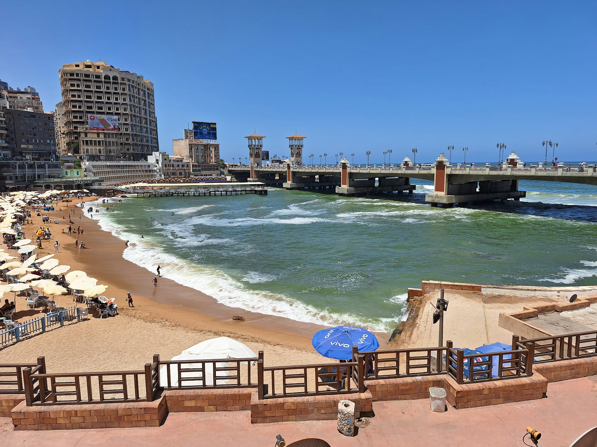 A panoramic view of a beach with a pier in the background