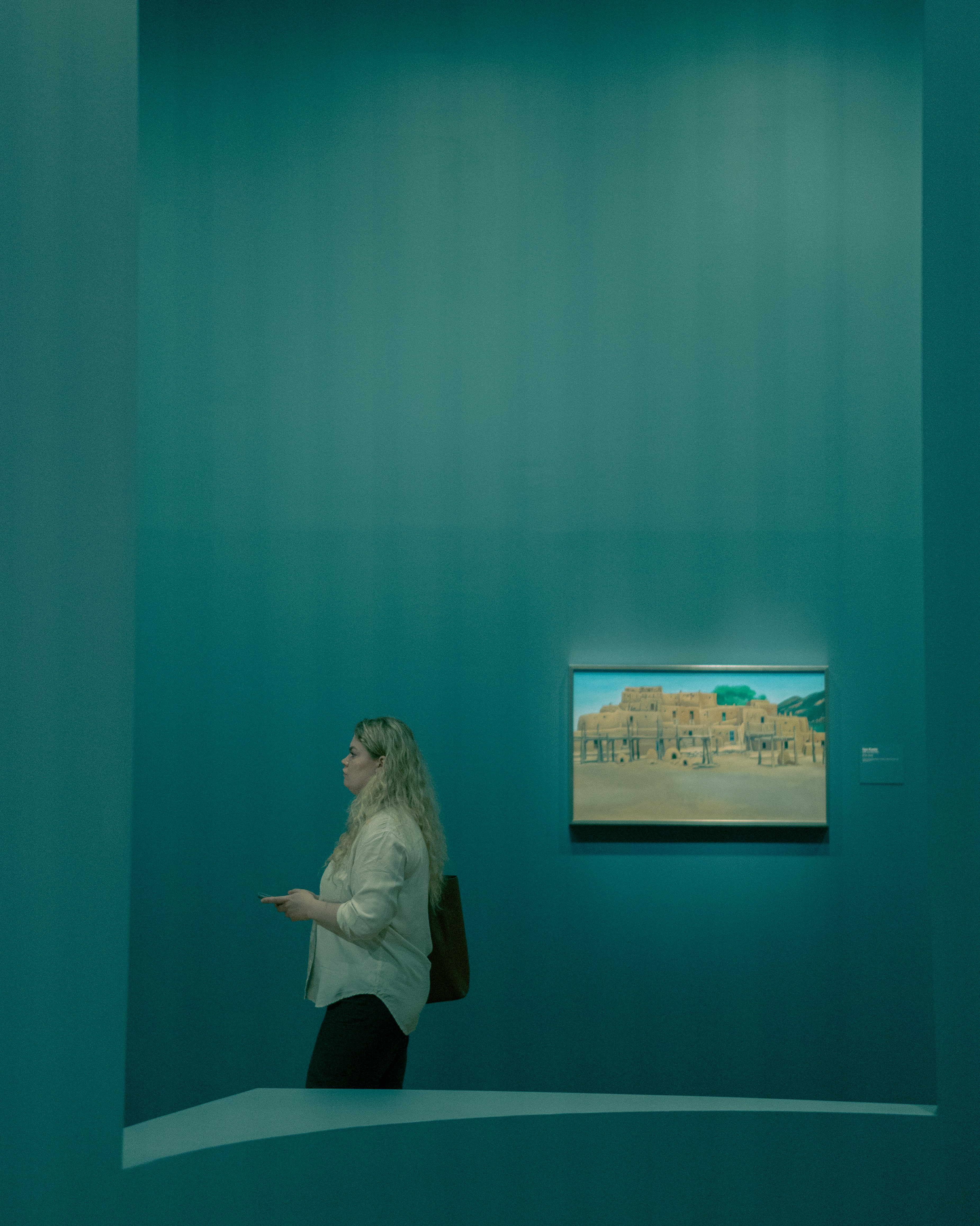 Une femme debout dans une pièce avec un tableau sur le mur