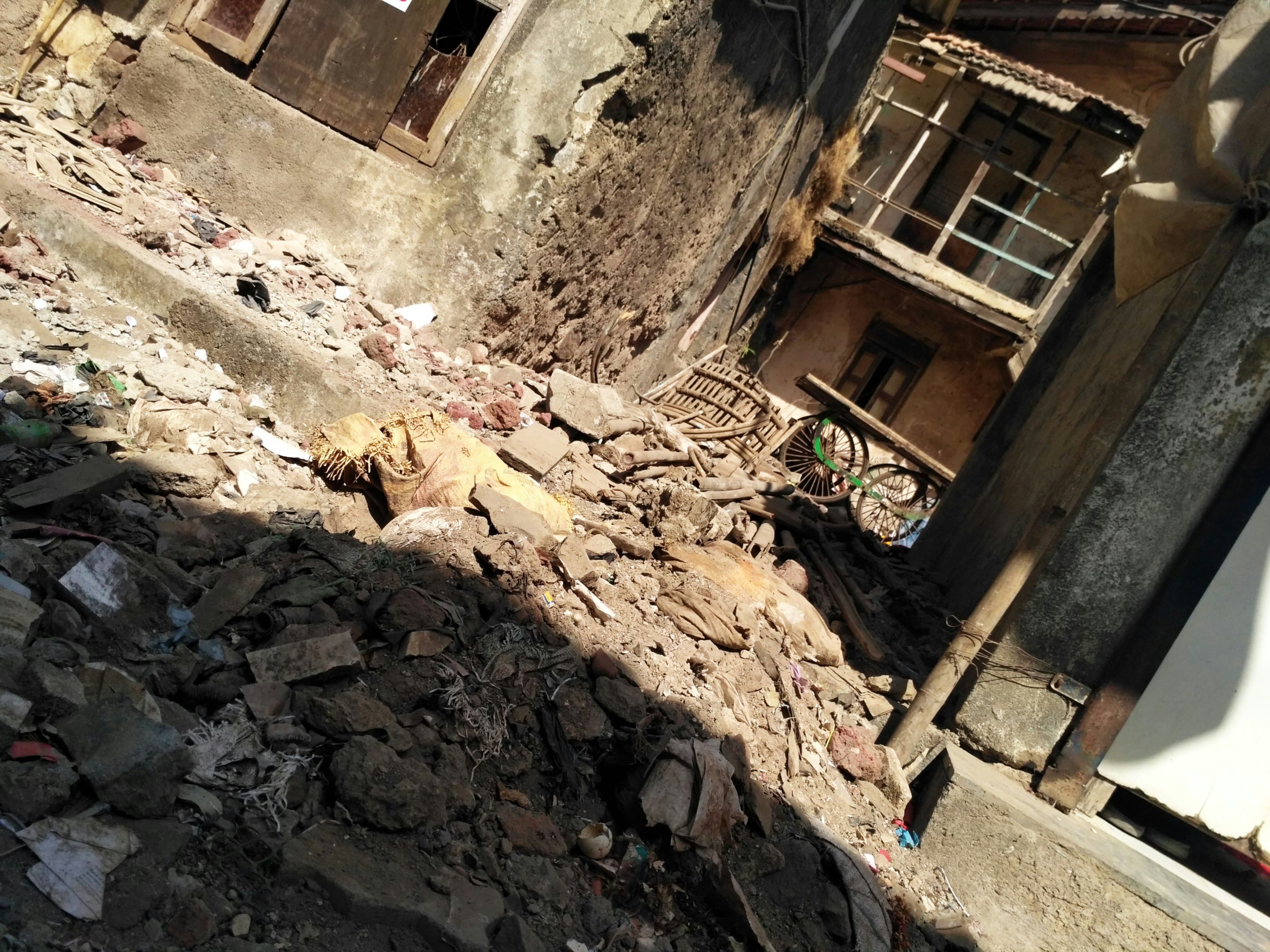 Pile of construction debris and rubble outdoors in overcast light, heavy shadows, gritty industrial environment