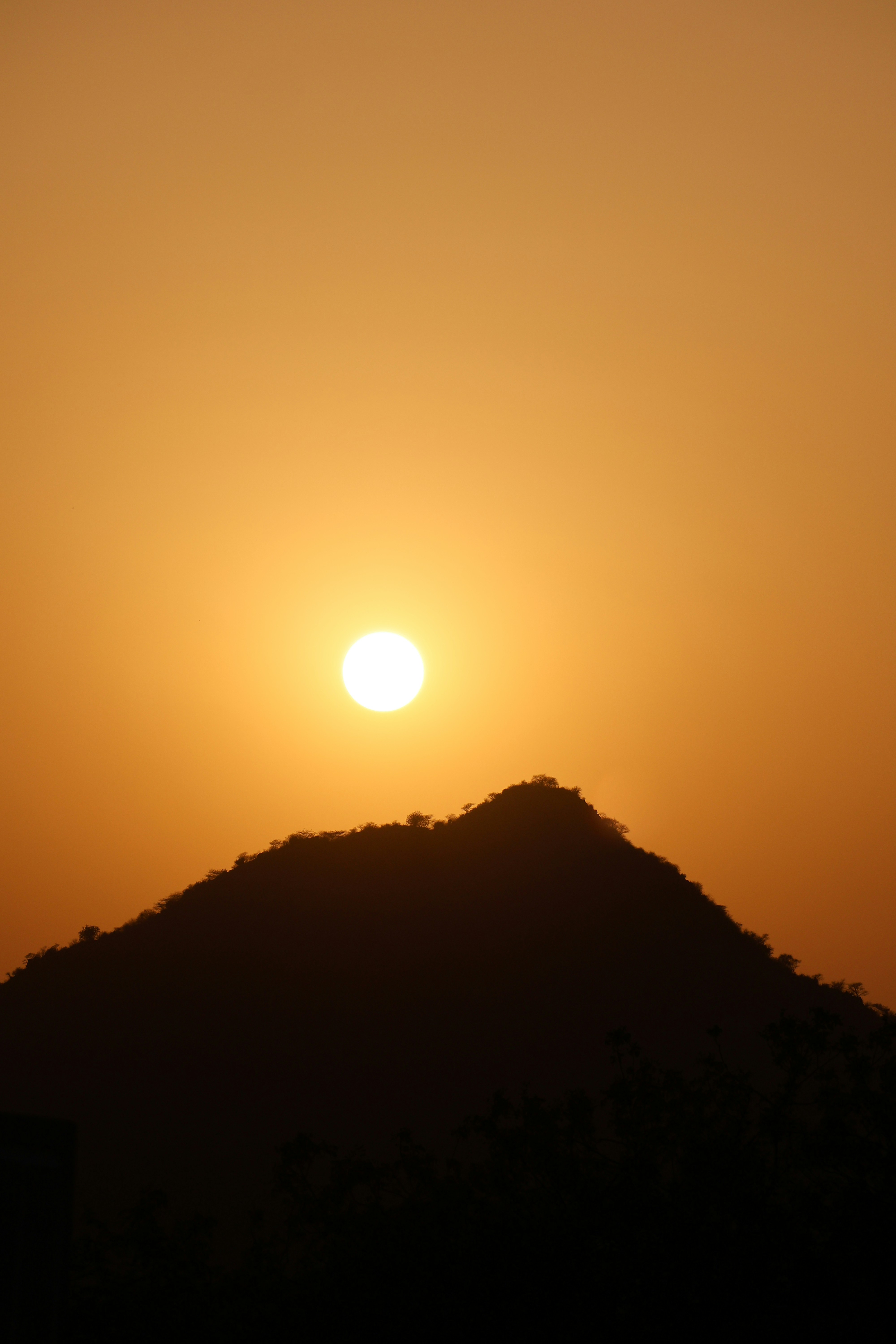 The sun is setting over a hill in the distance